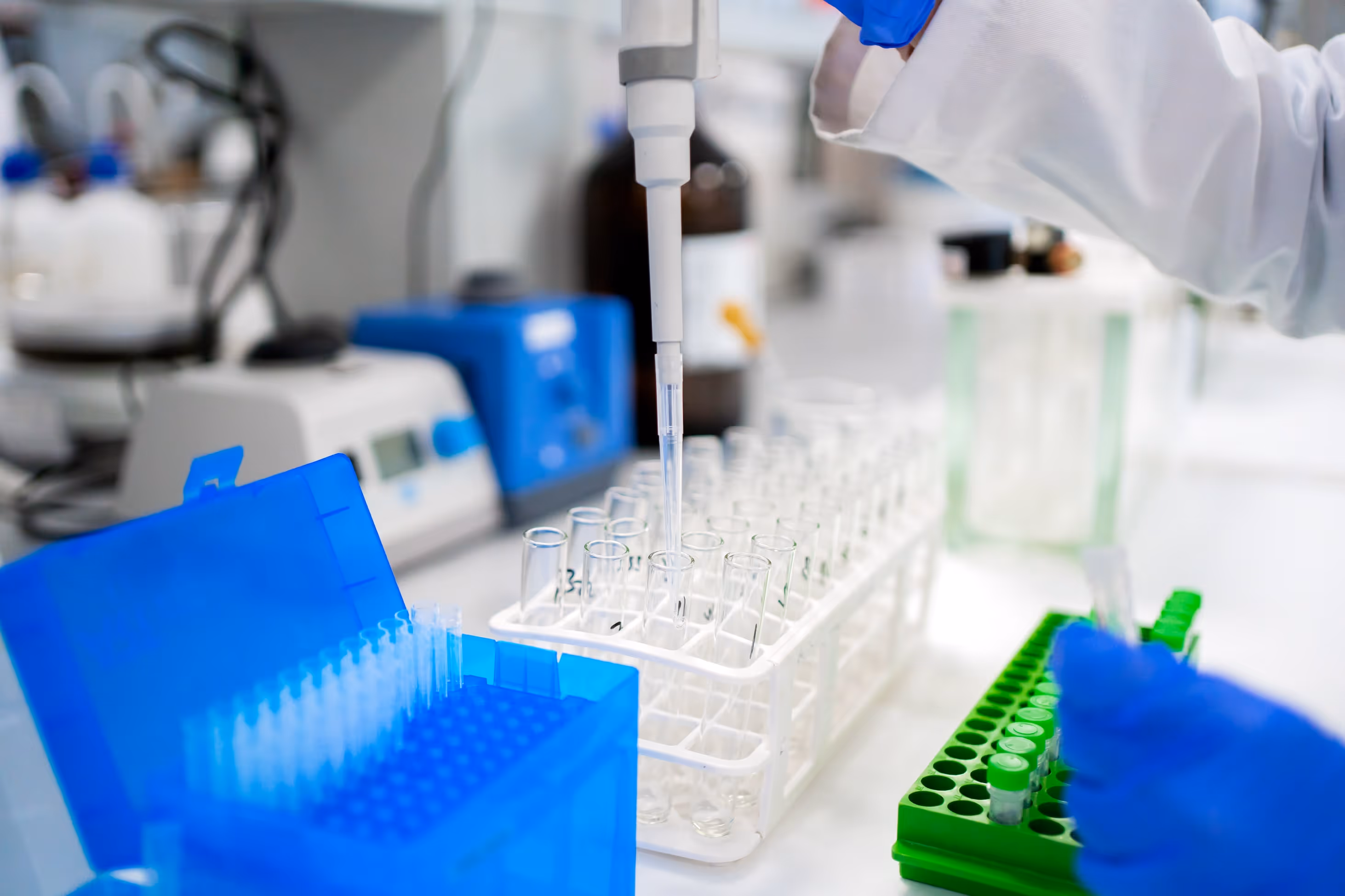 Laboratory scene—technician working under cGMP conditions, handling liquid samples and test tubes